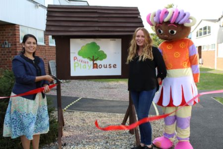 Priti Patel MP cutting the ribbon to declare Pickles Playhouse open, with help from new owner Marie Downes and a friend!