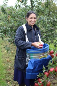 Priti Patel with fruit picker’s basket, helps to gather in the harvest.