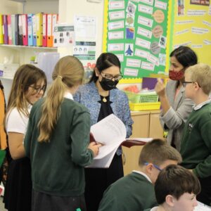 Pupils at Powers Hall Academy queue up to show off their handwriting skills to Priti Patel.