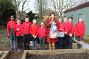 Pupils at St Andrew’s Jnr School, with Priti Patel MP in the School garden on Get Witham Growing day.