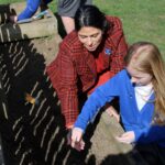 Priti helps a pupil at St Luke’s Primary School, Tiptree, to plant seeds from the basket she presented to the School on Get Witham Growing day.