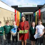 Witham MP Priti Patel with pupils outside Stanway Fiveways Primary School and the basket of seeds, tools and a book that she presented to the School on Get Witham Growing day.
